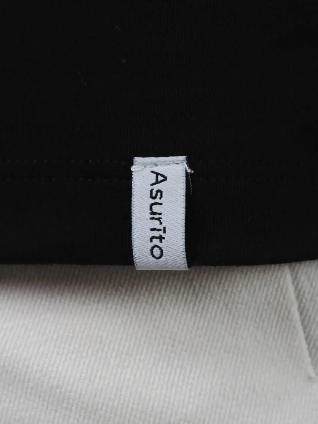 Woven Asurito label at the hem of a black tee