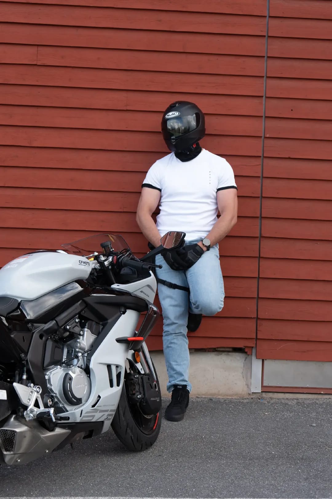 Rider in a white Asurito ringer tee beside a motorcycle